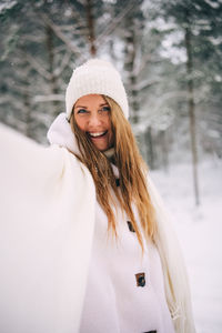 Portrait of smiling young woman standing in snow