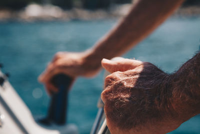 Cropped hands of man riding motorboat on sea