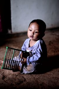 Cute boy looking away while sitting on floor