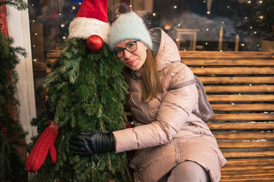 Portrait of smiling young woman holding christmas tree