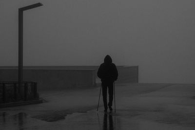 Rear view of silhouette woman standing by sea against sky