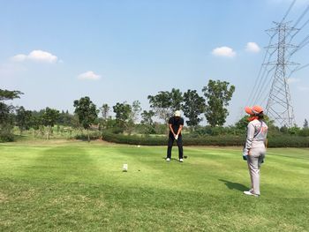 People playing soccer on golf course against sky