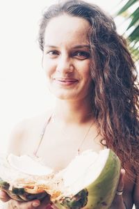 Close-up portrait of smiling young woman holding coconut