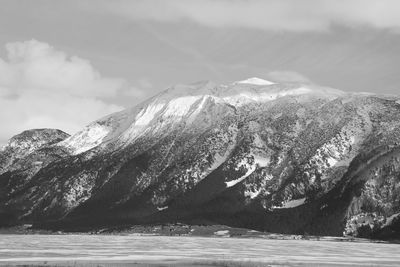 Sea by mountain against sky
