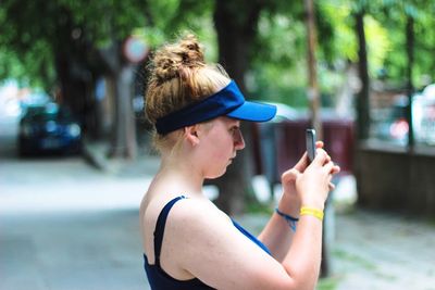 Close-up of woman using mobile phone by trees at park