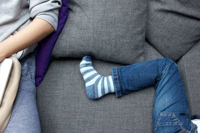 Midsection of men with friend resting on sofa at home