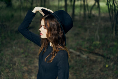 Young woman wearing hat standing against trees