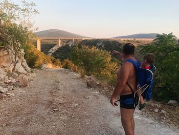 Rear view of men walking on road against sky