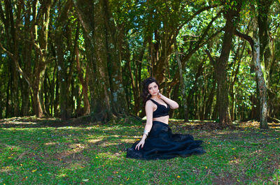 Portrait of woman sitting on land in forest