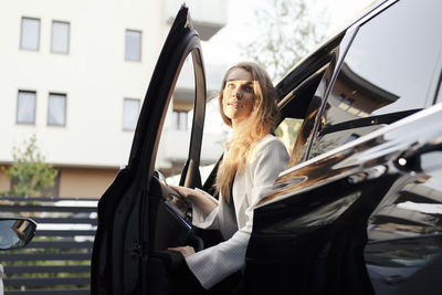 Portrait of smiling woman standing by car