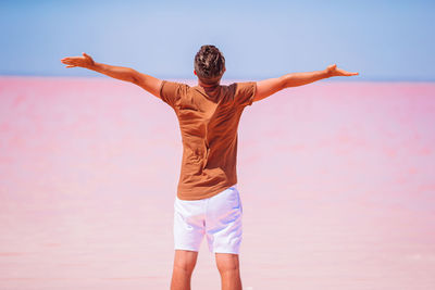 Rear view of man standing by sea against sky