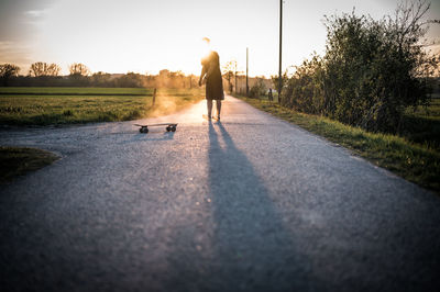 Man with skateboard on road against sky