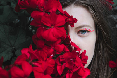 Portrait of young woman with red geranium flowers