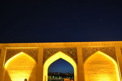 Low angle view of illuminated bridge against clear sky at night