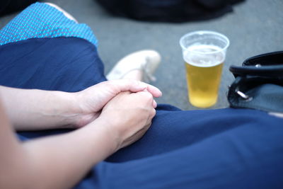 Cropped image of woman sitting by beer glass on floor