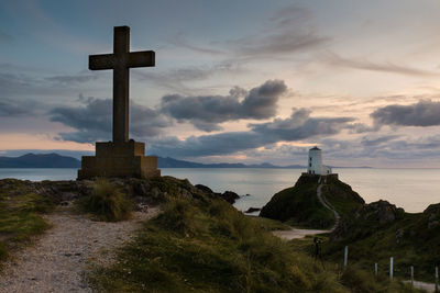 Cross on shore against sky