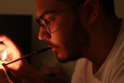 Close-up of young man igniting tobacco product