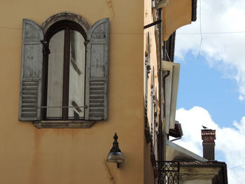 Low angle view of street light by building against sky