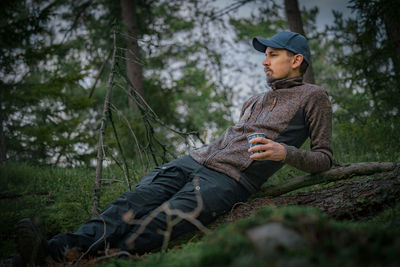 Low angle view of man sitting on rock