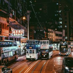 Illuminated railroad tracks by street in city at night