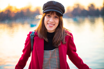 Portrait of smiling young woman standing against lake