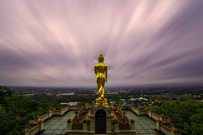 Buddha statue against cloudy sky during sunset