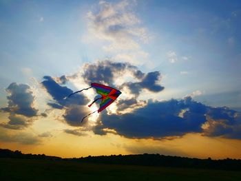 Low angle view of kite flying in sky during sunset