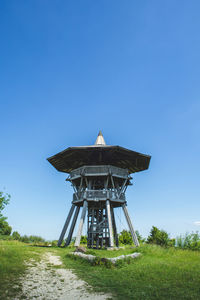 Traditional windmill on field against clear blue sky