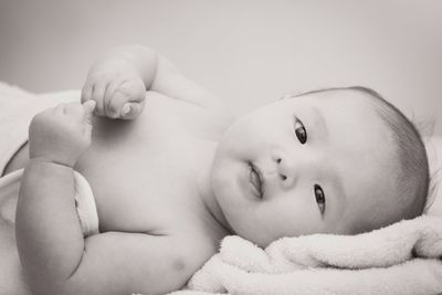 Close-up portrait of cute baby boy lying on bed