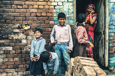 Portrait of friends standing against brick wall