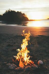 Bonfire at beach against sky during sunset