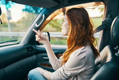 Midsection of woman using mobile phone in car