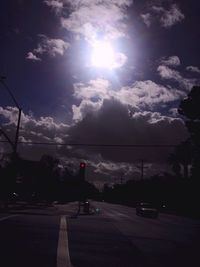 Cars on road against cloudy sky