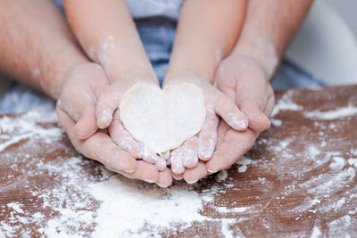 Top view father and child's hand, cut out heart shaped cookies from dough