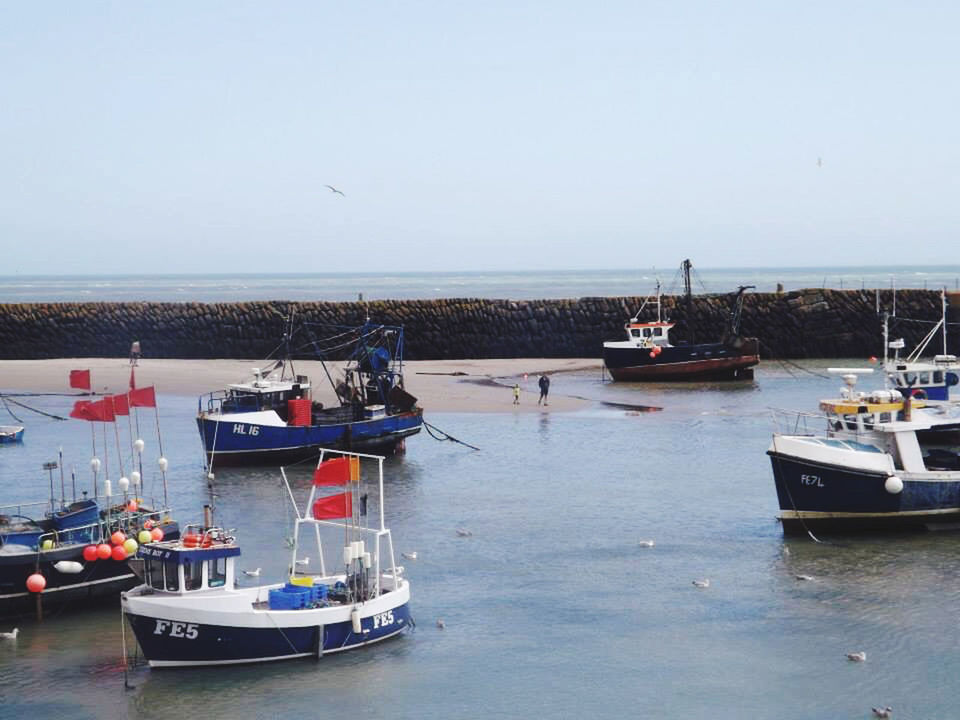 BOATS MOORED ON SEA AGAINST CLEAR SKY