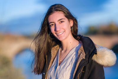 Portrait of young woman standing against sky