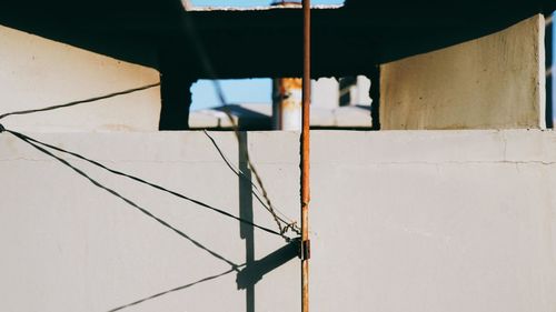 Close-up of metallic structure against building on sunny day