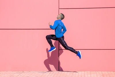 Sporty man exercising on fuchsia wall