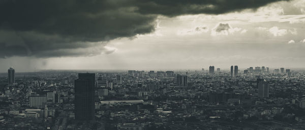 Aerial view of cityscape against cloudy sky