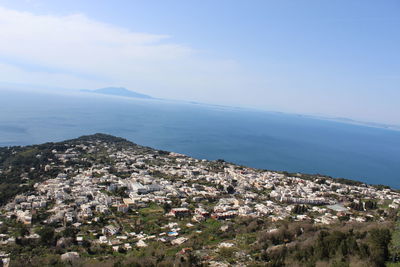 Aerial view of townscape by sea against sky