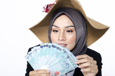 Portrait of young woman wearing hat against white background