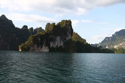 Scenic view of sea by mountains against sky