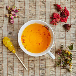 View from above of a cup of herbal tea, with the herbs scattered around