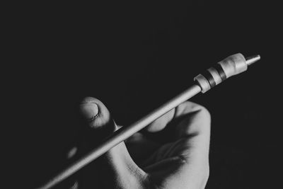 Close-up of hand holding lighting equipment against black background