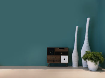 Vases by sideboard against blue wall at home