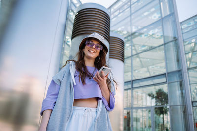 Young cool girl holding and using mobile phone. smiling woman texting with friends