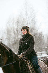 Woman riding horse on snow covered field