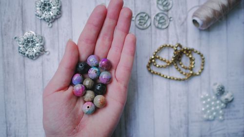 Cropped hand of person holding beads over table