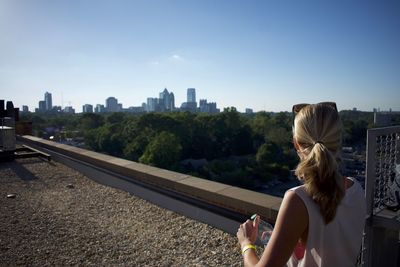 Rear view of woman looking at city while standing on terrace