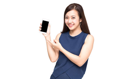 Portrait of smiling young woman using phone against white background